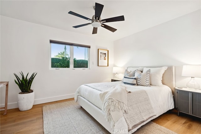 bedroom with wood finished floors, a ceiling fan, and baseboards