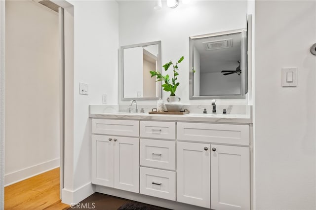 bathroom featuring wood finished floors, a sink, baseboards, and double vanity