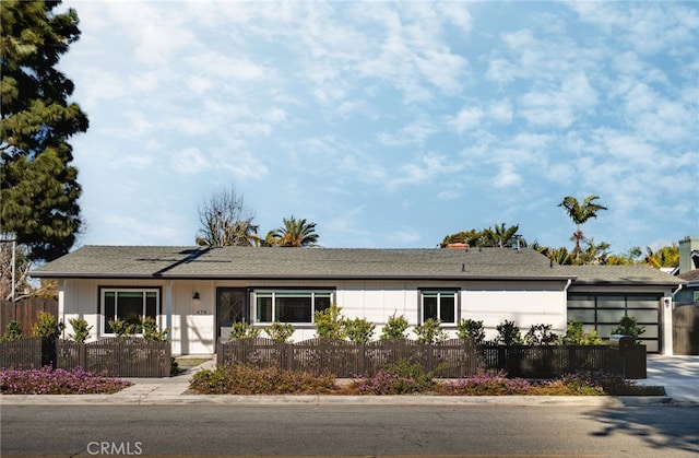 ranch-style house featuring a fenced front yard, driveway, a garage, and solar panels