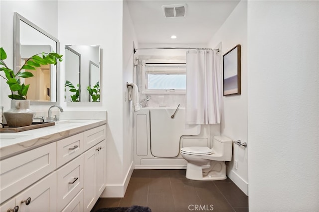 bathroom featuring double vanity, visible vents, toilet, a sink, and walk in shower