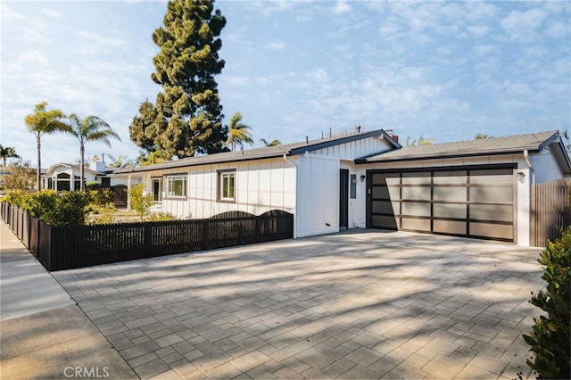 view of front of house featuring a garage, decorative driveway, a fenced front yard, and board and batten siding