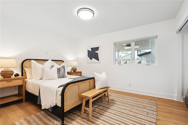 bedroom featuring light wood finished floors and baseboards