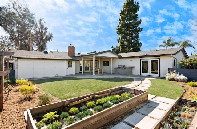 rear view of house with a yard, a garden, a patio, and french doors