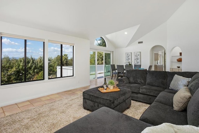 tiled living room featuring visible vents, arched walkways, baseboards, built in shelves, and high vaulted ceiling