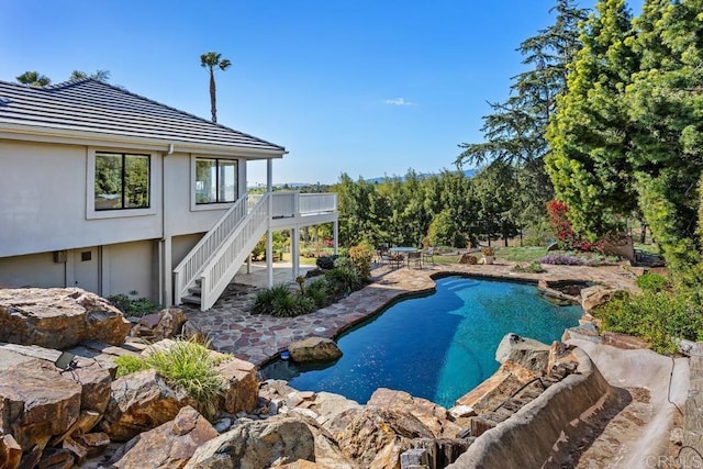 outdoor pool with a deck, stairway, and a patio area