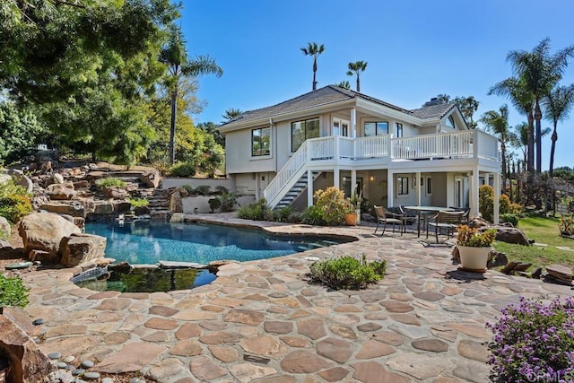 back of house featuring stairway, an outdoor pool, and a patio