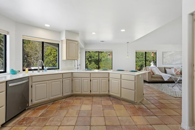 kitchen featuring light countertops, stainless steel dishwasher, a sink, and a healthy amount of sunlight