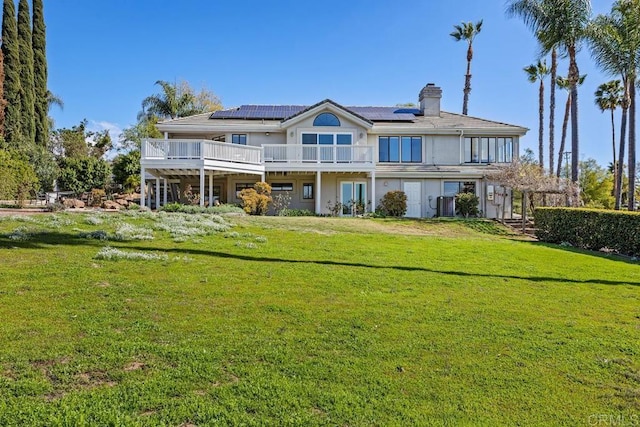 back of house featuring solar panels, a yard, a chimney, and a wooden deck