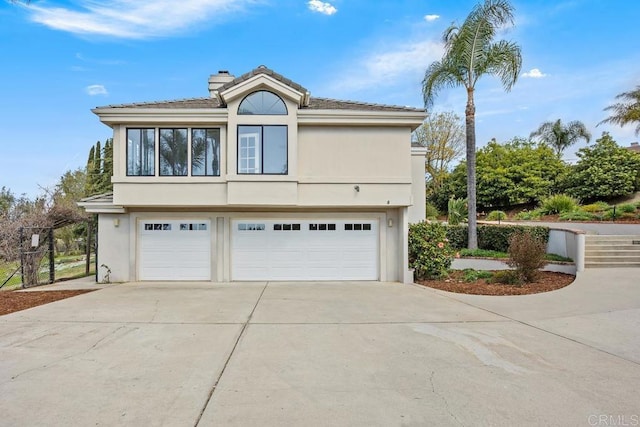 view of home's exterior featuring a garage, concrete driveway, a chimney, and stucco siding