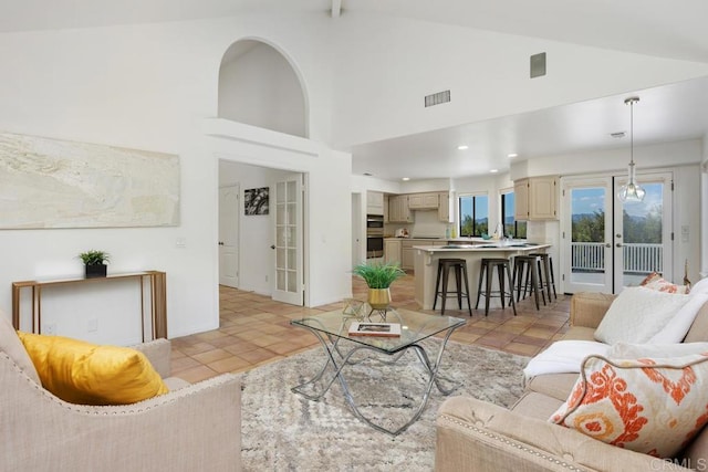 living room with french doors, light tile patterned floors, visible vents, high vaulted ceiling, and baseboards