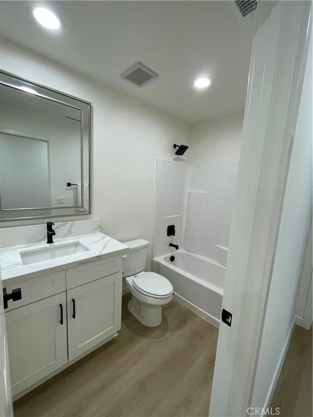 full bathroom featuring toilet, wood finished floors, vanity, visible vents, and  shower combination