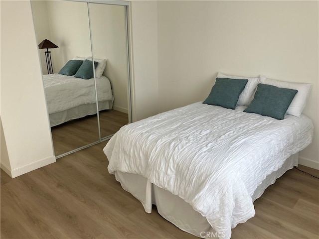 bedroom featuring a closet, baseboards, and wood finished floors