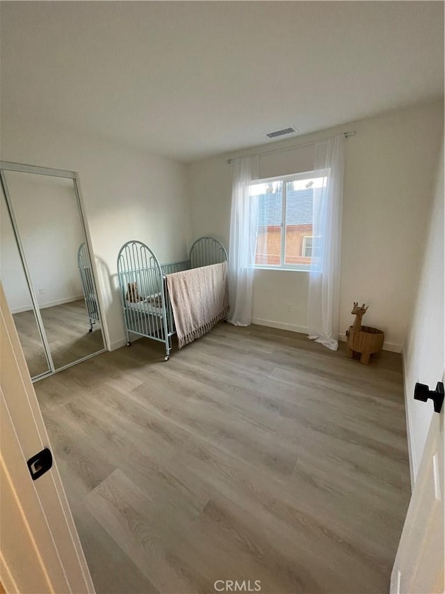 unfurnished bedroom featuring visible vents and wood finished floors