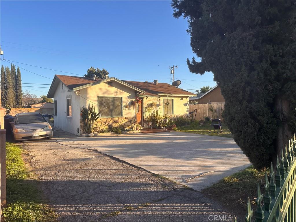 view of front of property featuring stucco siding, driveway, and fence