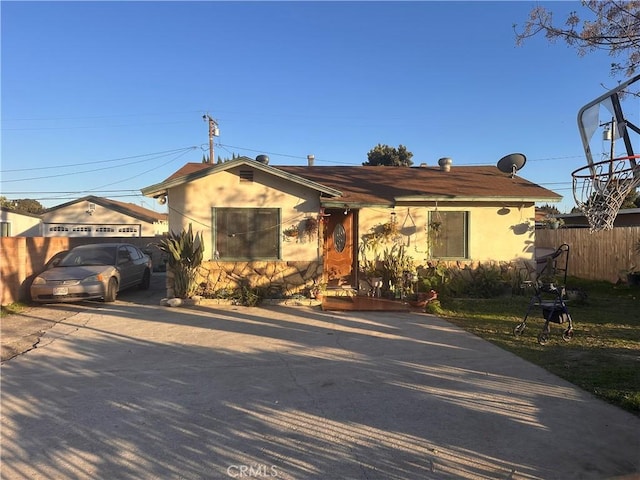 ranch-style home featuring stucco siding, concrete driveway, and fence