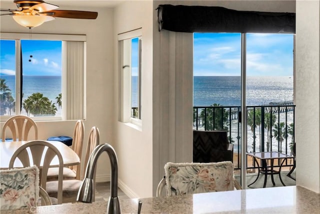 dining room with plenty of natural light, a water view, and a ceiling fan