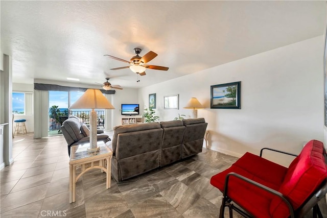 living room featuring baseboards, ceiling fan, and a healthy amount of sunlight