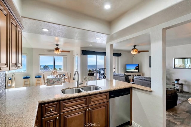 kitchen featuring a peninsula, dishwasher, ceiling fan, and a sink
