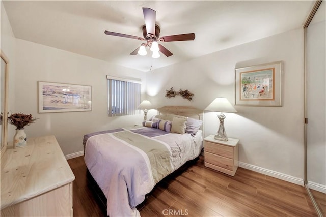 bedroom featuring ceiling fan, a closet, wood finished floors, and baseboards