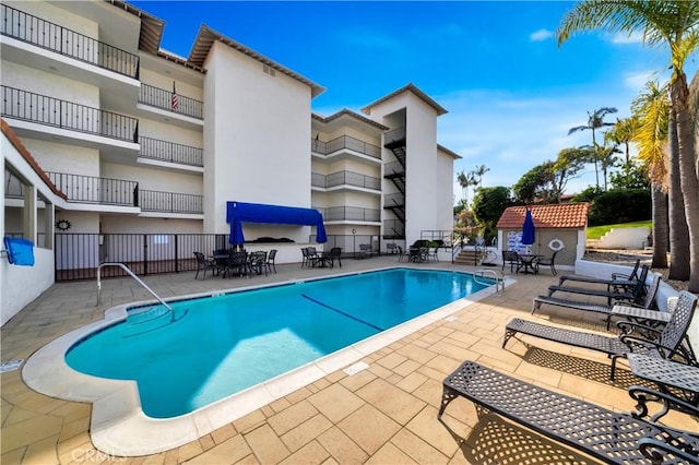 pool with a patio area and fence