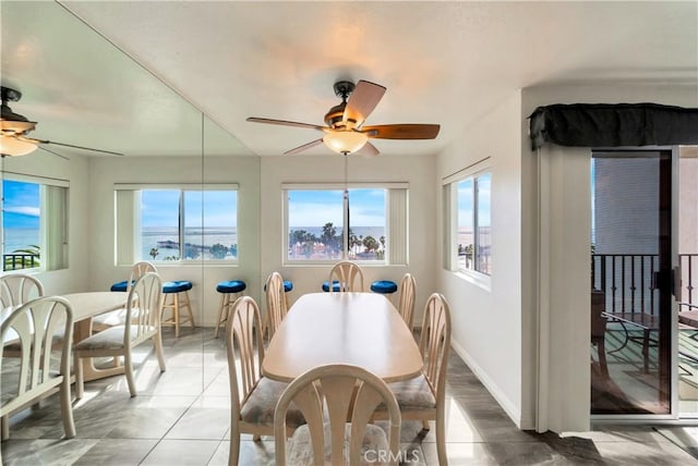 tiled dining area with ceiling fan and baseboards