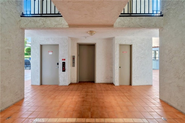 spare room featuring elevator, a healthy amount of sunlight, and a towering ceiling