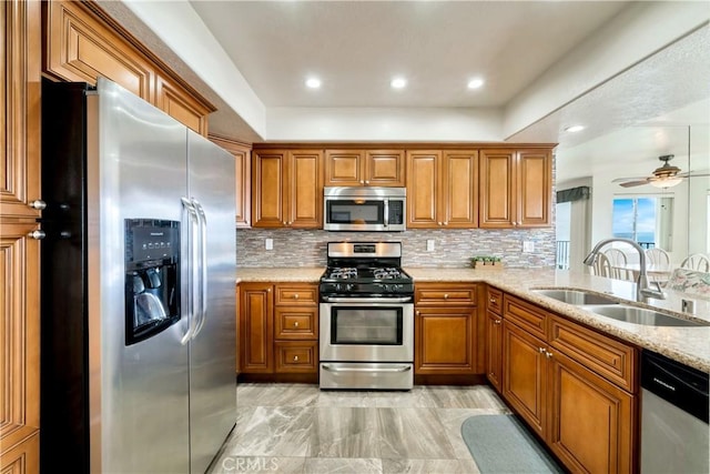 kitchen with stainless steel appliances, brown cabinets, a sink, and backsplash