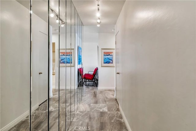 hall featuring baseboards and track lighting