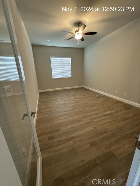 spare room with dark wood-style floors, baseboards, and a ceiling fan