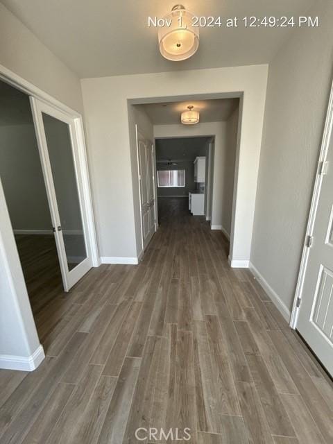 corridor featuring baseboards and wood finished floors