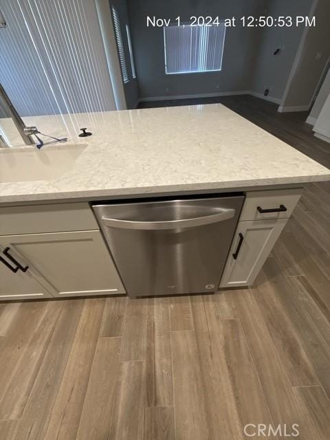 kitchen featuring white cabinetry, dishwasher, a sink, and wood finished floors