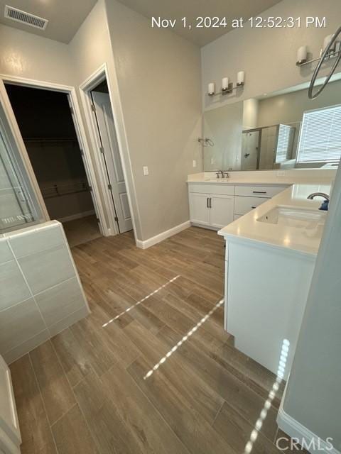 full bath featuring a shower stall, visible vents, a sink, and wood finished floors