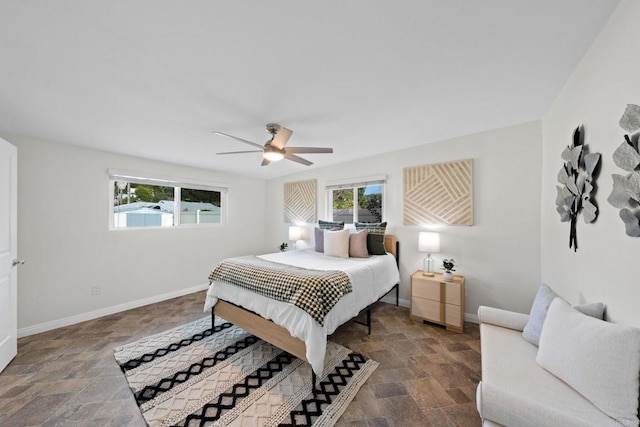 bedroom with baseboards, multiple windows, and stone finish floor