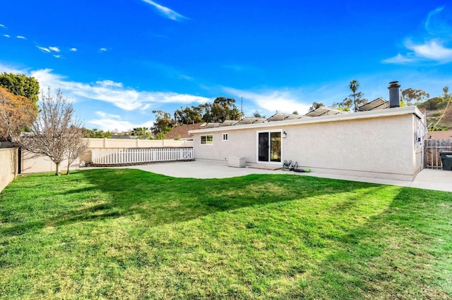 back of property with stucco siding, a patio, a fenced backyard, and a lawn