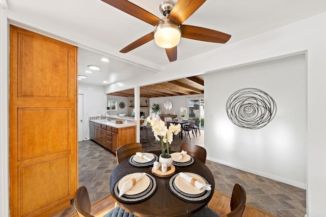 dining space featuring beam ceiling, stone finish flooring, and baseboards