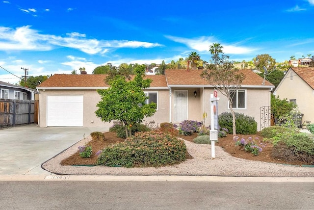 ranch-style home featuring concrete driveway, an attached garage, fence, and stucco siding