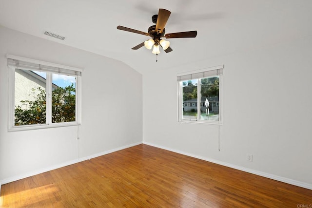 spare room featuring a healthy amount of sunlight, visible vents, and wood finished floors