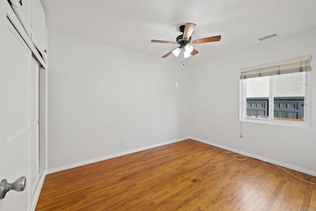 empty room featuring light wood-style flooring, visible vents, ceiling fan, and baseboards