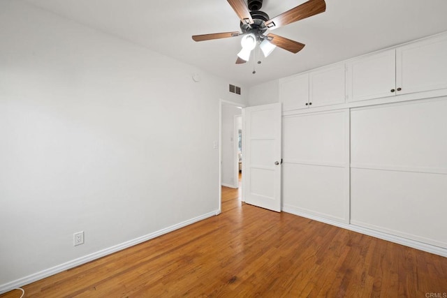 unfurnished bedroom with visible vents, baseboards, a ceiling fan, wood finished floors, and a closet