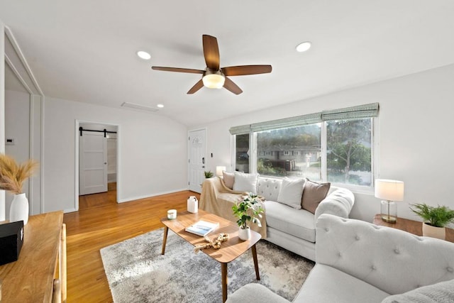 living room with ceiling fan, a barn door, recessed lighting, baseboards, and light wood-type flooring