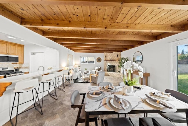 dining area featuring beamed ceiling, a fireplace, and wood ceiling