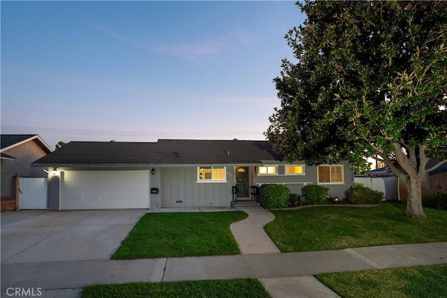 ranch-style home featuring concrete driveway, a lawn, board and batten siding, fence, and a garage