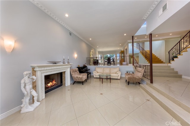 living area with a warm lit fireplace, baseboards, stairs, and visible vents