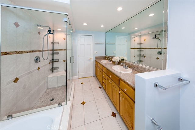 full bath featuring a stall shower, double vanity, a sink, and tile patterned floors