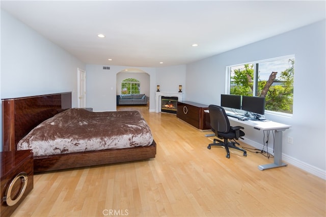 bedroom with recessed lighting, a glass covered fireplace, visible vents, and light wood-style floors