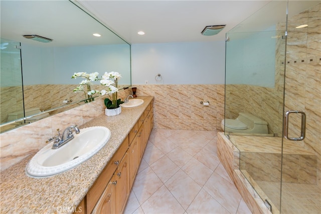 bathroom featuring double vanity, a stall shower, a sink, and tile walls