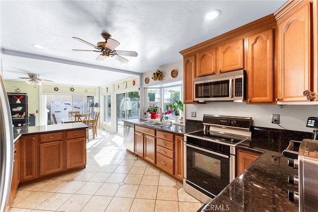 kitchen featuring appliances with stainless steel finishes, brown cabinetry, a sink, and a ceiling fan