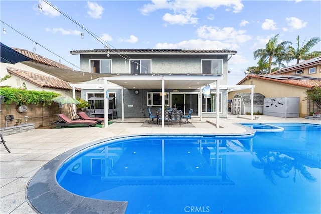 rear view of house featuring a storage shed, a fenced in pool, a fenced backyard, a patio area, and outdoor dining space