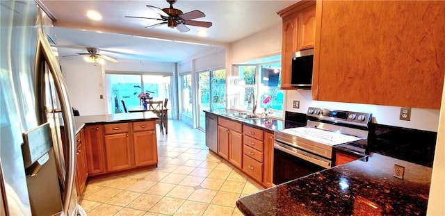 kitchen featuring dark stone counters, ceiling fan, appliances with stainless steel finishes, a sink, and light tile patterned flooring