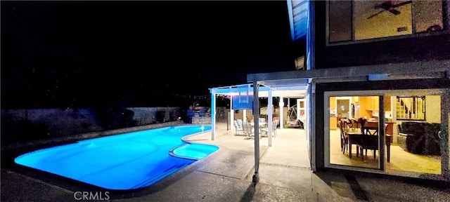 pool at night featuring an outdoor pool and a patio